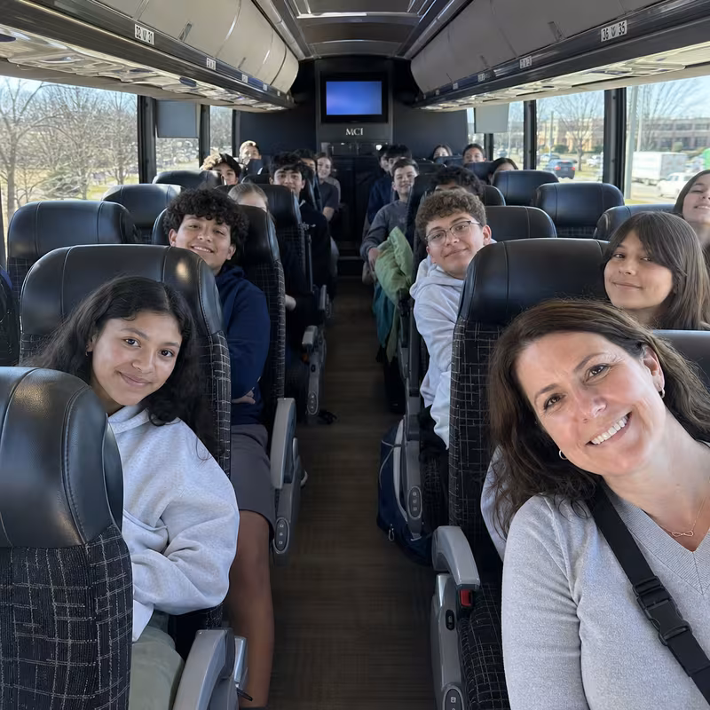 Group boarding a white charter bus for School Transportation transportation in Arlington